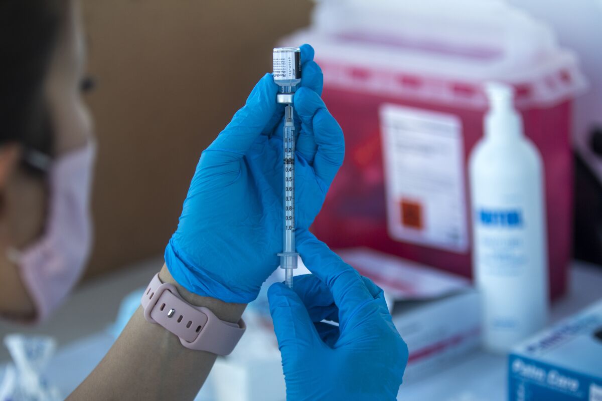 A healthcare worker prepares a COVID-19 vaccine dose. 