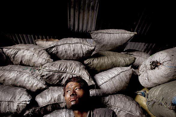 A man sits covered in charcoal from loading it into bags for sale in the slum area of Hlaing Thaya on May 2, 2009 in Yangon, Myanmar. The country's government spends only 0.3% of its gross domestic product on health, the lowest amount worldwide, according to the 2008 United Nations Development Program survey.