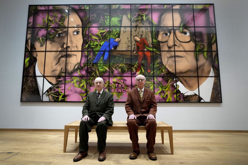 Gilbert and George sit with their artwork called On The Bench in their exhibition called The Paradisical Pictures at the opening of The Gilbert & George Centre in east London, Friday, March 24, 2023. (AP Photo/Kirsty Wigglesworth)