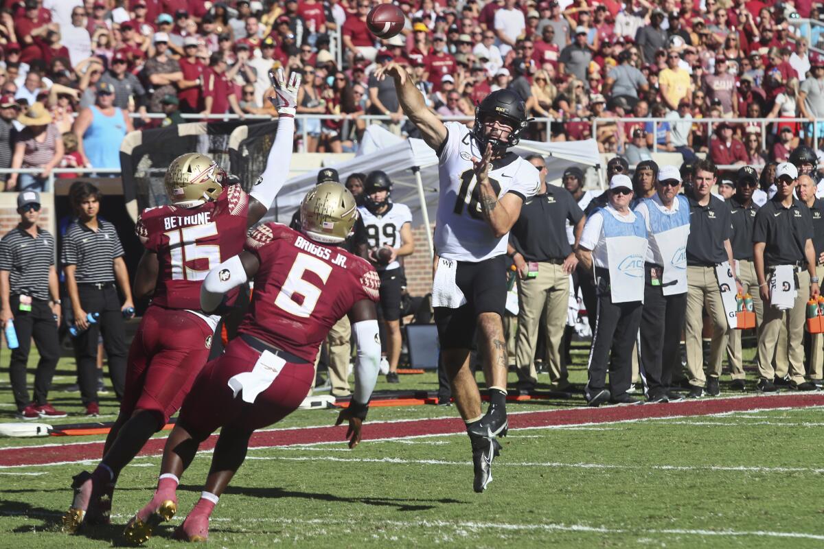 Wake Forest quarterback Sam Hartman leaps to throw a pass over Florida State linebacker Tatum Bethune (15) and defensive end Dennis Briggs, Jr. (6) in the first half of an NCAA college football game, Saturday, Oct. 1, 2022, in Tallahassee, Fla. (AP Photo/Phil Sears)