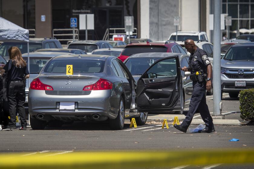 FULLERTON, CALIF. -- MONDAY, AUGUST 19, 2019: Evidence markers are placed around an Infinity as police and crime scene investigators investigate a homicide on the first day of school on the Cal State Fullerton campus where a man with black hair, black pants and a black shirt assaulted someone with a deadly weapon at 8:30 a.m. in the parking lot near the College Park building, campus police said. Photo taken in Fullerton, Calif., on Aug. 19, 2019. The man was last seen headed toward the Marriott area. (Allen J. Schaben / Los Angeles Times)