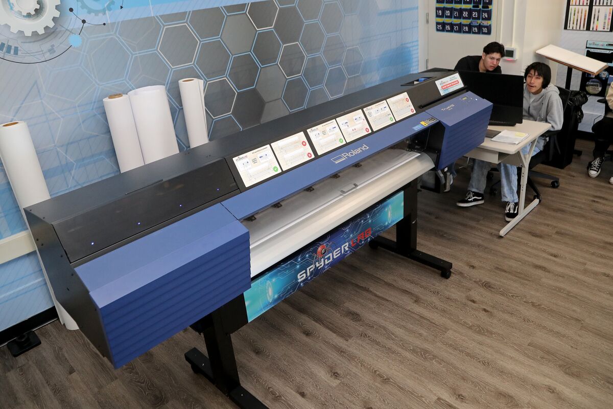 Davian Gonzalez, 17, top left, and Christian Martinez, 17, top right, use an eco-solvent printing and cutting machine.