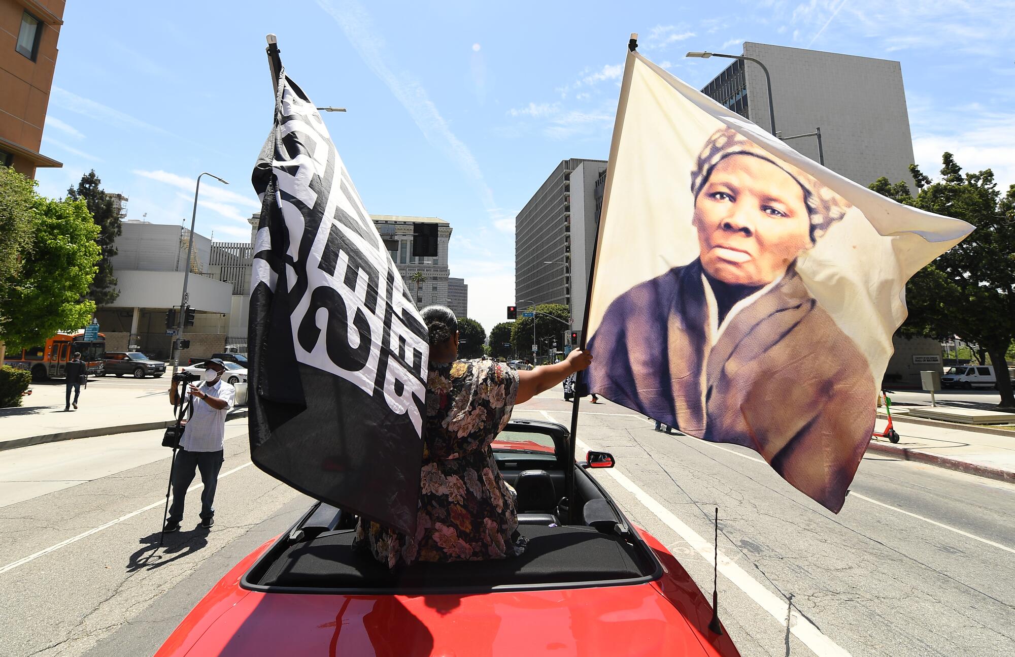 A person waves a Black Lives Matter flag and another one with the image of Harriet Tubman.