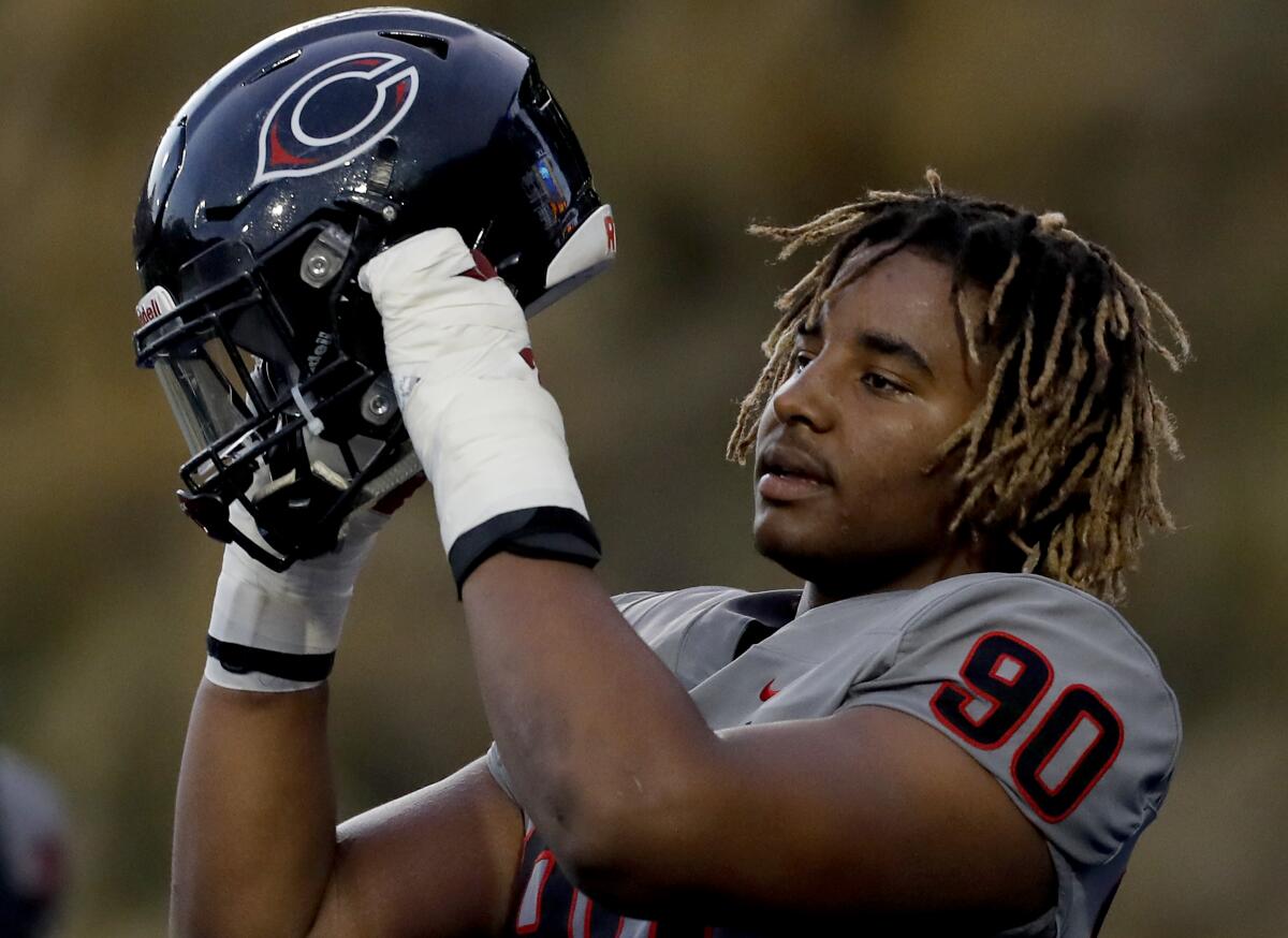 Corona Centennial defensive end Korey Foreman puts on his helmet before a game.