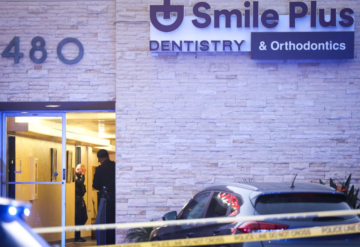 Officer holds head in hand Thursday evening while police investigated a shooting inside Smile Plus Dentistry & Orthodontics