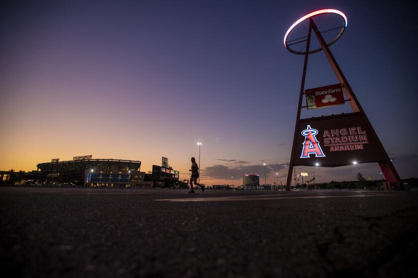 Anaheim, CA - August 24: A runner passes by as the sun sets behind Angel Stadium.
