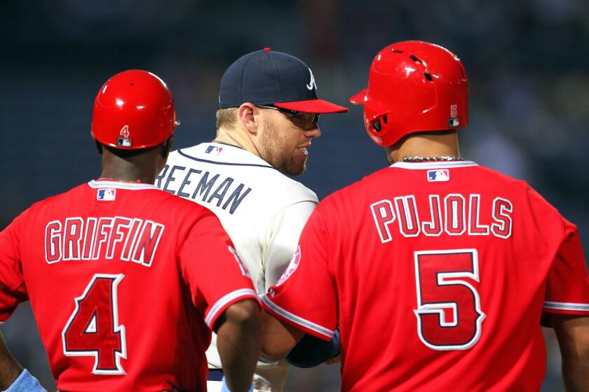 Albert Pujols (5) talks with Braves first baseman Freddie Freeman, center, after hitting a single in the third inning. Pujols was two for four at the plate with a run scored in the Angels' 7-3 loss to Atlanta.