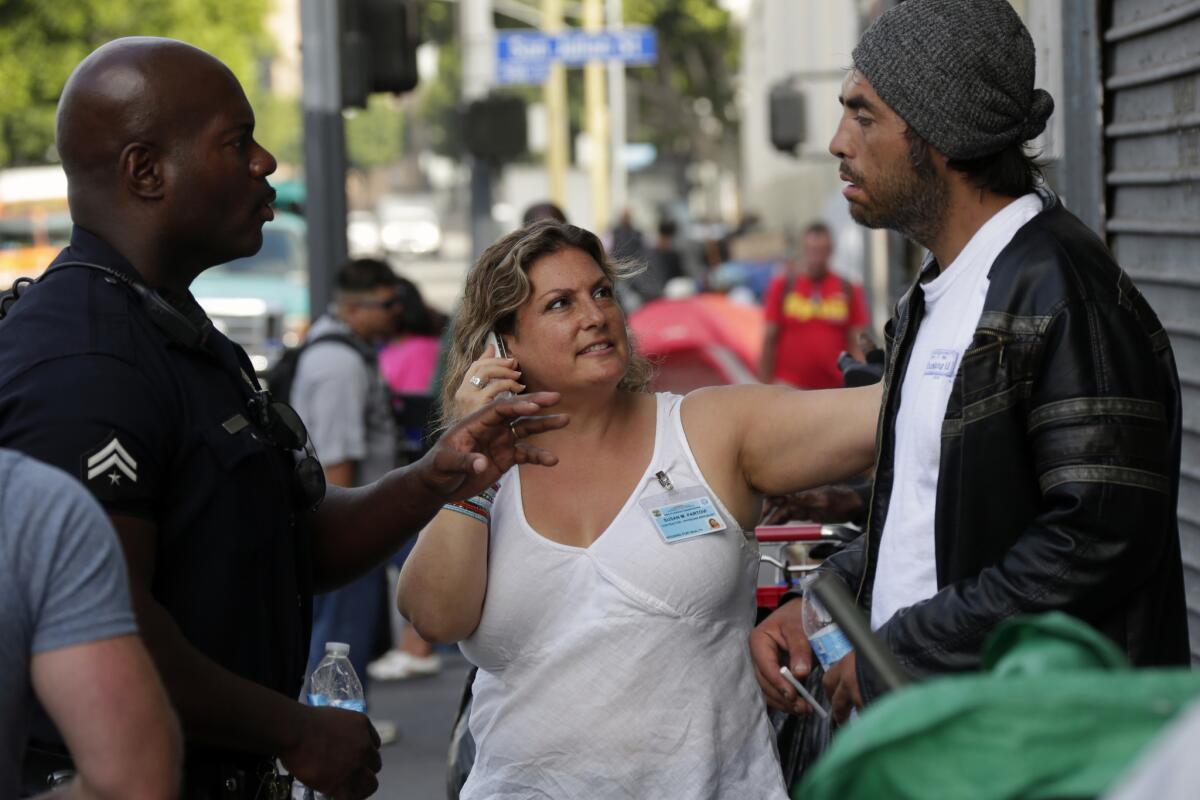 LAPD Officer Deon Joseph, left, and Dr. Susan Partovi of the L.A. County Department of Health Services check on 40-year-old Luis Trejas, who was found dazed and stumbling on the sidewalk Wednesday.