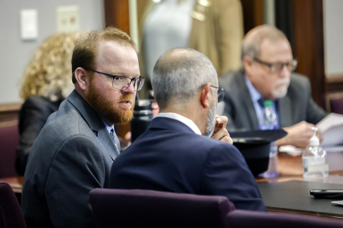 Travis McMichael, left, speaks with his attorney.