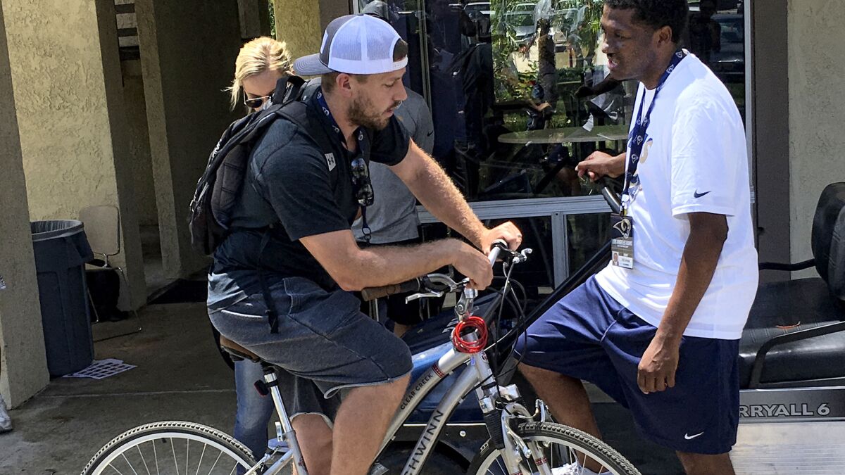 Rams quarterback Case Keenum (on bicycle) chats with team spokesman Artis Twyman on Thursday at UC Irvine.