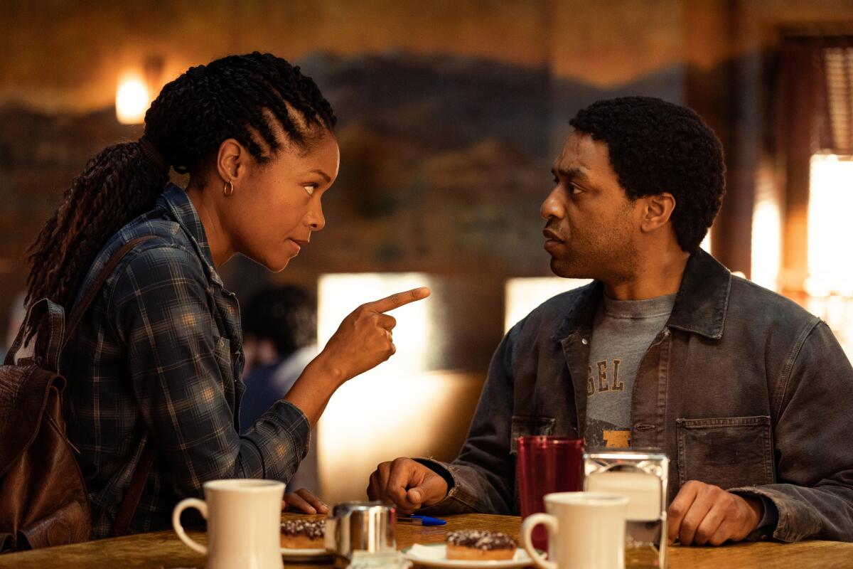 A woman points at a man at a diner table