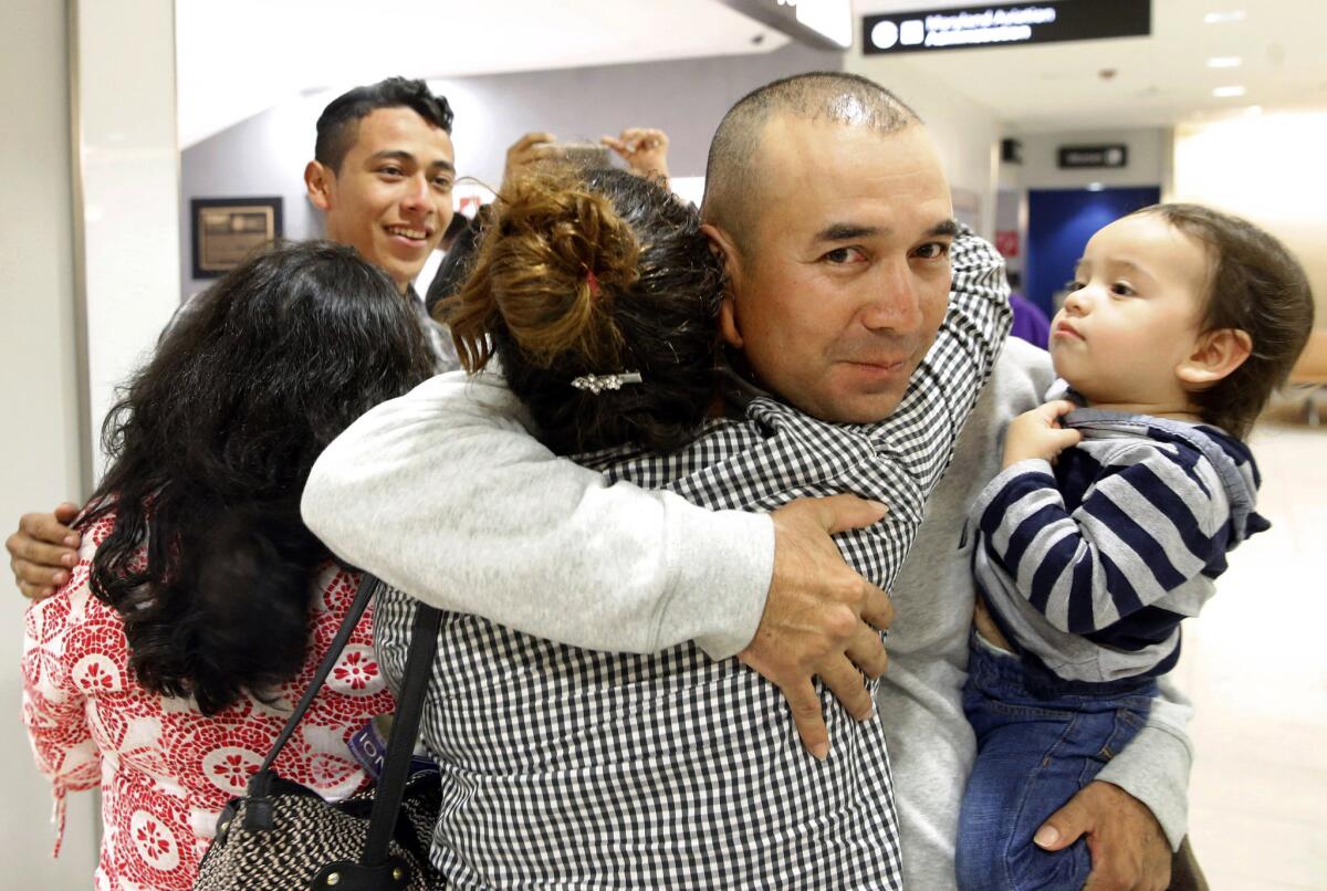 Gabriel Mejía abraza a su hija Wendy, de 16 años, mientras sostiene en un brazo a su hijo Elías, de un año, en el aeropuerto de Baltimore el 12 de noviembre del 2015. Mejía pudo traer a su familia gracias a un programa del gobierno estadounidense. (AP Photo/Patrick Semansky)