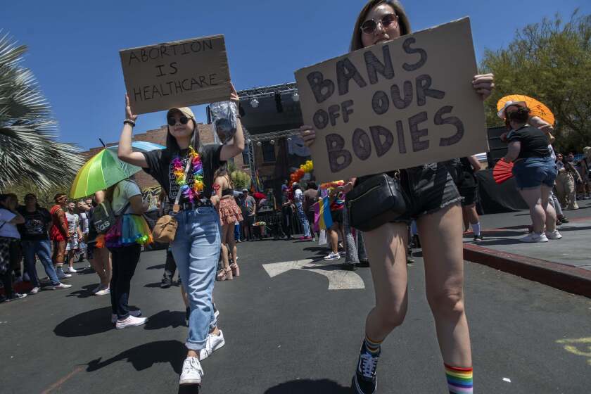 Rachel Esconde, left, of Anaheim, and Chantalle Sheung, right, of Anaheim, came prepared for the OC Pride Parade and Festival to show what they think about the recent Supreme Court ruling in Santa Ana on Saturday, June 25, 2022. (Photo by Paul Rodriguez)