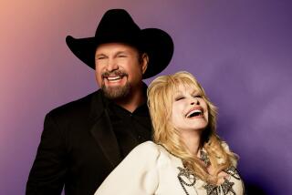 Garth Brooks wearing a black cowboy hat and outfit while laughing with Dolly Parton, wearing a tight white outfit with stars