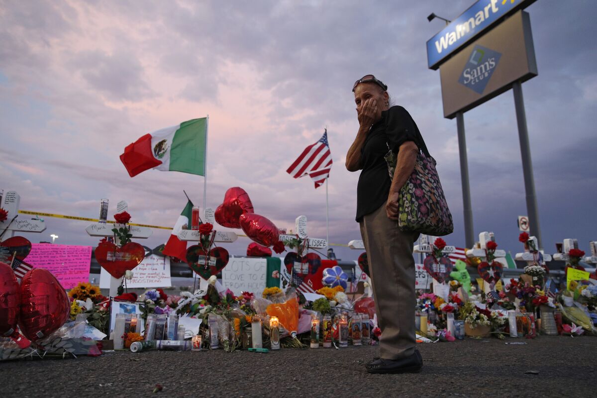 FILE - In this Aug. 6, 2019 file photo, Catalina Saenz wipes tears from her face as she visits a makeshift memorial near the scene of a mass shooting at a shopping complex in El Paso, Texas. El Paso is marking the year anniversary of the a shooting at a crowded Walmart by remembering the 23 people killed. Authorities have said the gunman traveled from his home near Dallas to target Latinos in the Texas border city on Aug. 3, 2019. (AP Photo/John Locher, File)