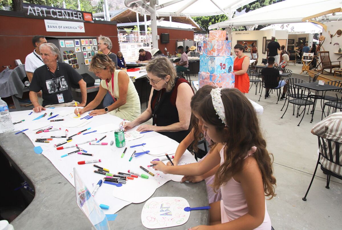 Guests take part in arts and crafts during the Festival of Arts 90th anniversary celebration on Saturday in Laguna Beach.