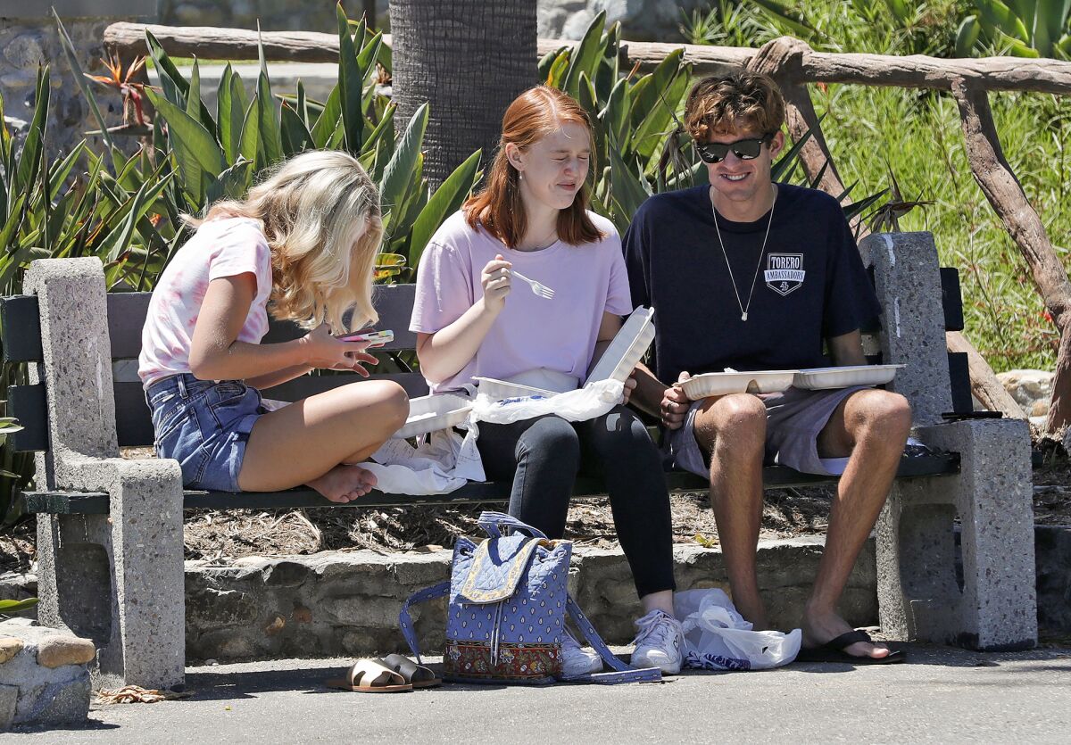Three teens have lunch at Heisler Park in Laguna Beach on Thursday.