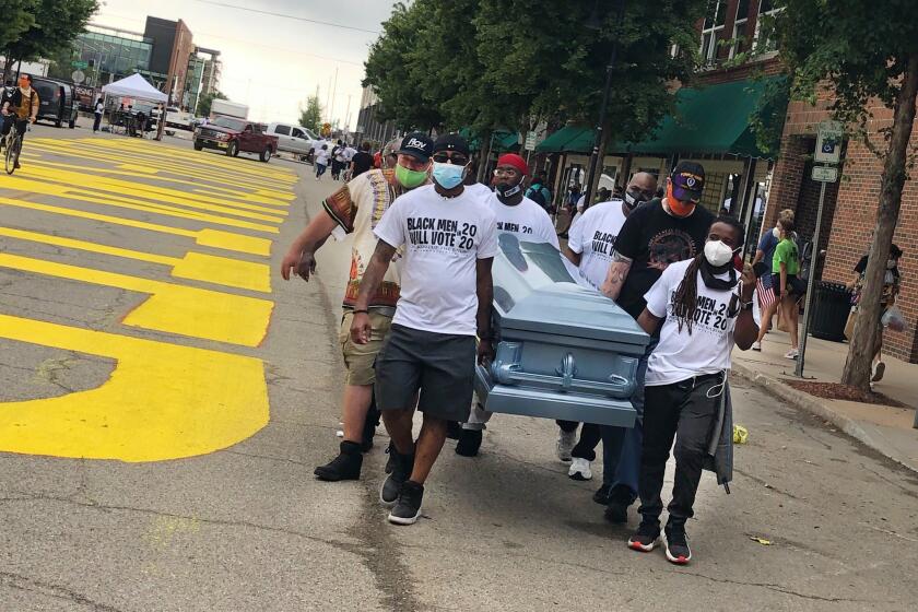 Volunteers from a Dallas-based non-profit carry an empty coffin past a new Black Lives Matter sign painted on Greenwood Avenue for Juneteenth. The mens' leader, Bruce Carter, said they were sending a message with the coffin: "We should all receive justice."