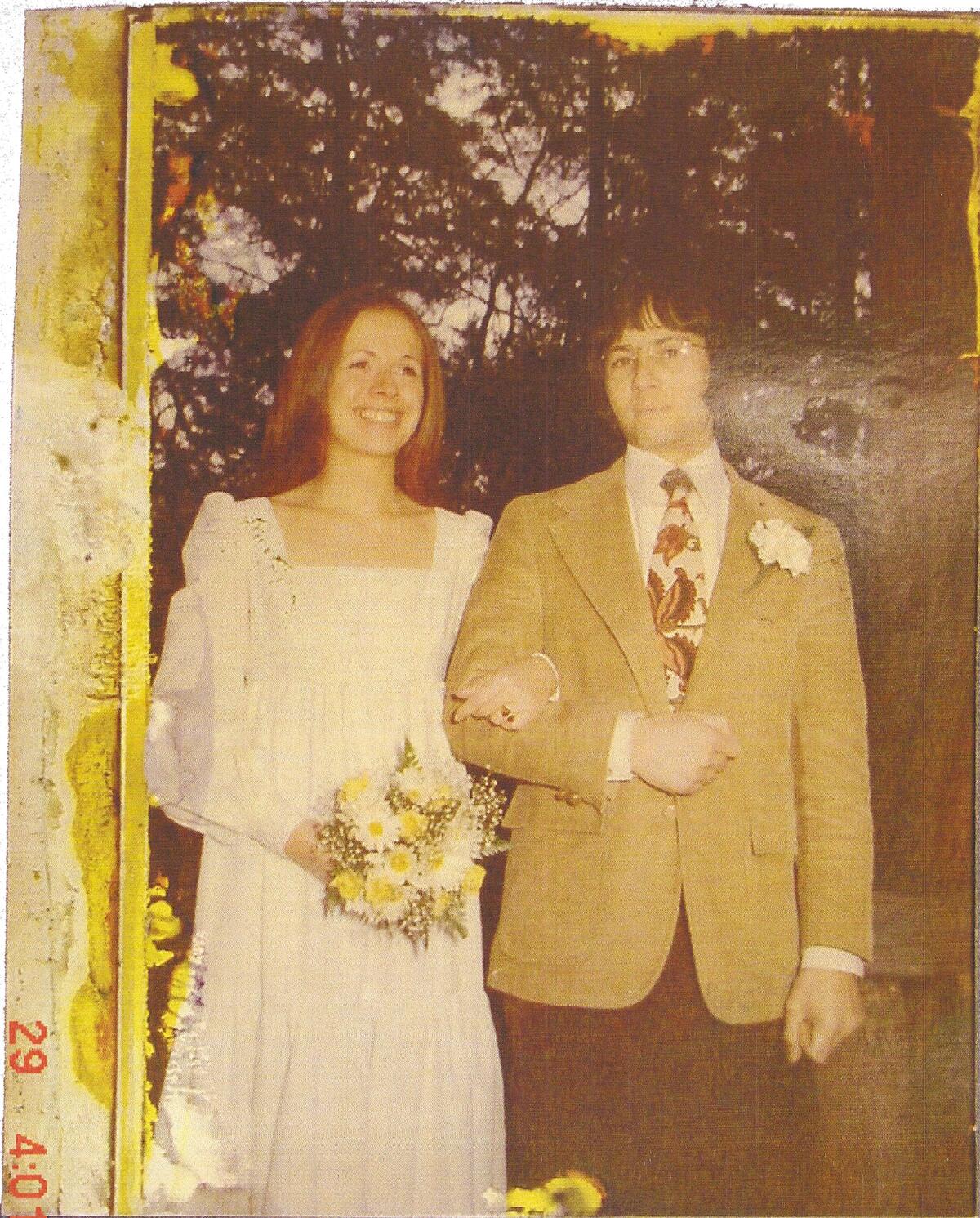 Kathleen Durst, wearing a wedding dress and holding flowers, stands next to Robert Durst.