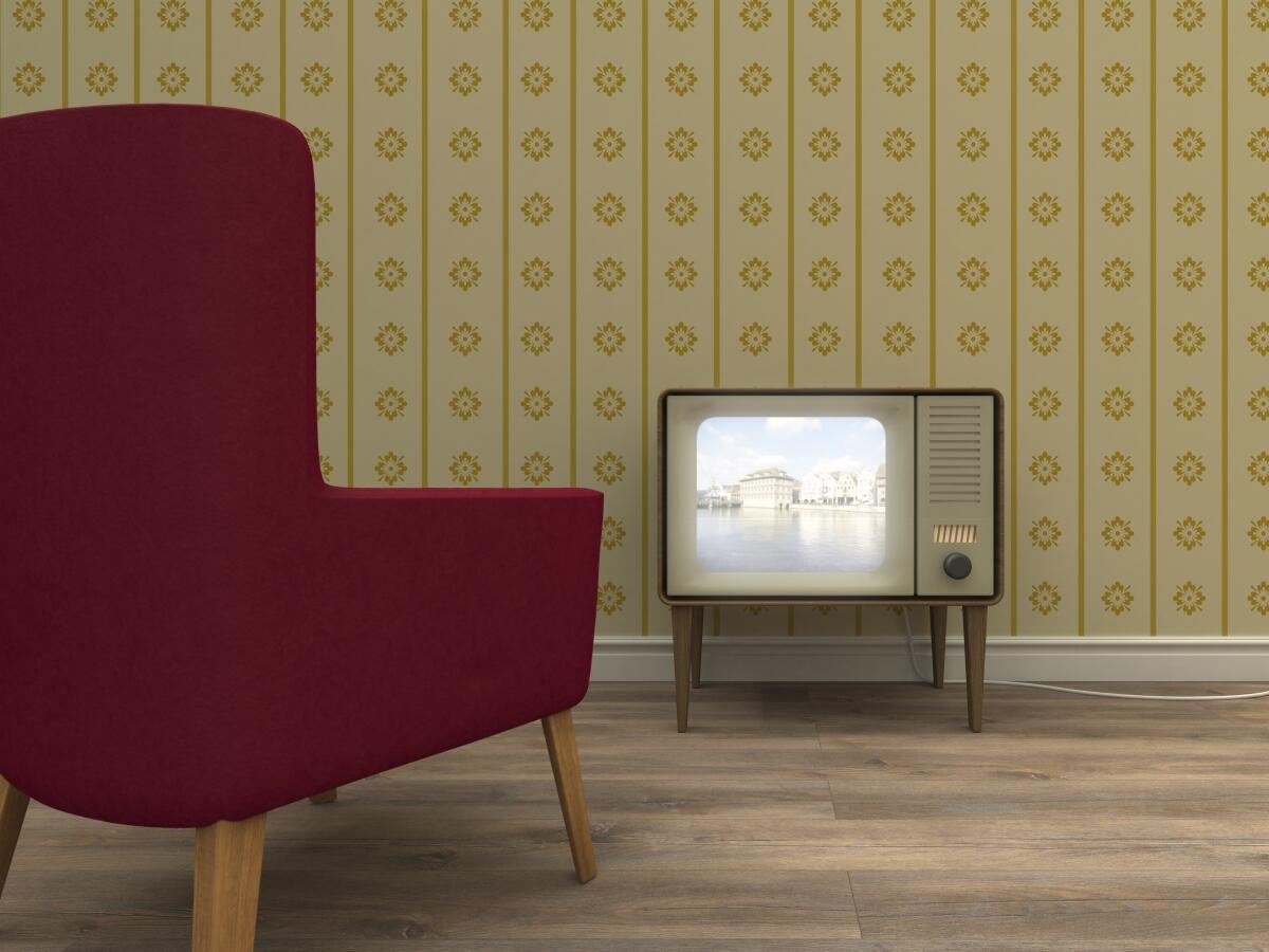 Old television and red armchair in a retro styled living room.