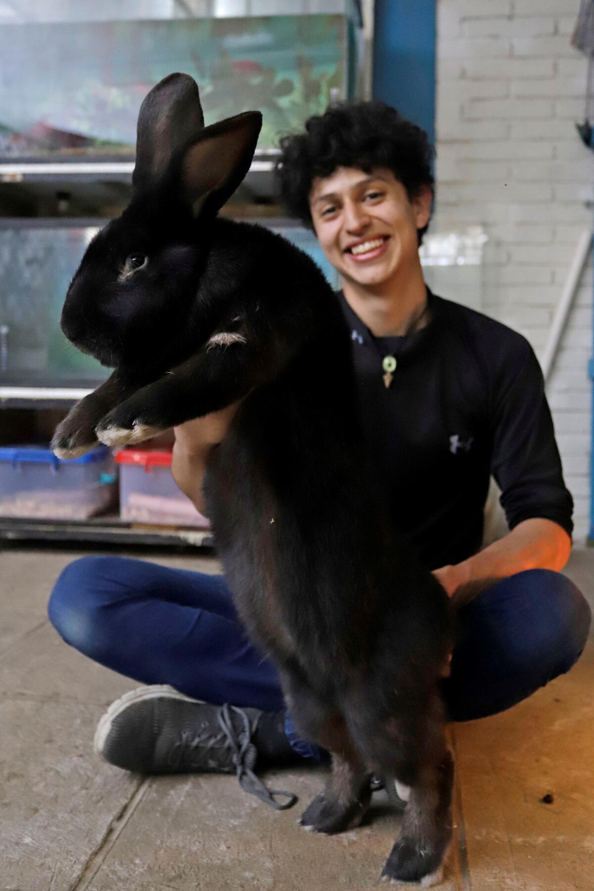 Fotografía que muestra al joven Kiro Yakin, mientras enseña una cría de conejo Flandes