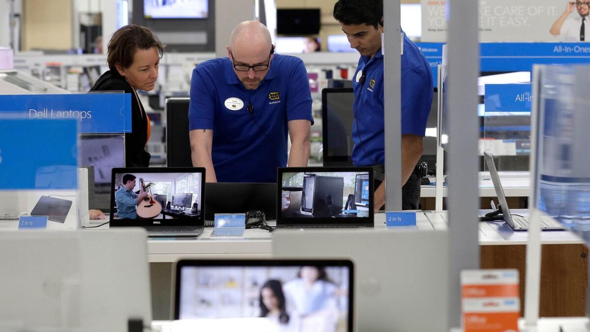 In this May 23 photo, employees assist a customer at Best Buy in Cary, N.C.