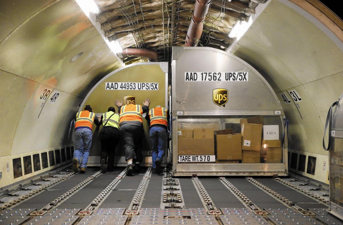 UPS spokeswoman Susan Rosenberg said there were some isolated areas in the first week of December where the number of packages coming in exceeded the company’s projections, causing a couple days of delay. Above, a UPS container full of packages is placed inside a plane in Louisville, Ky.