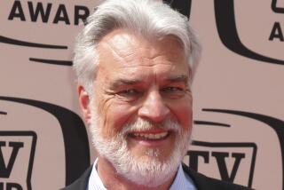 A silver-haired Richard Moll arrives at an event in a black jacket, blue-striped shirt and patterned blue tie