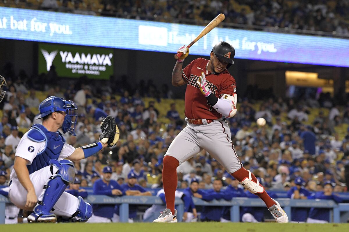 Arizona Diamondbacks' Ketel Marte is hit by a pitch as Dodgers catcher Will Smith watches.