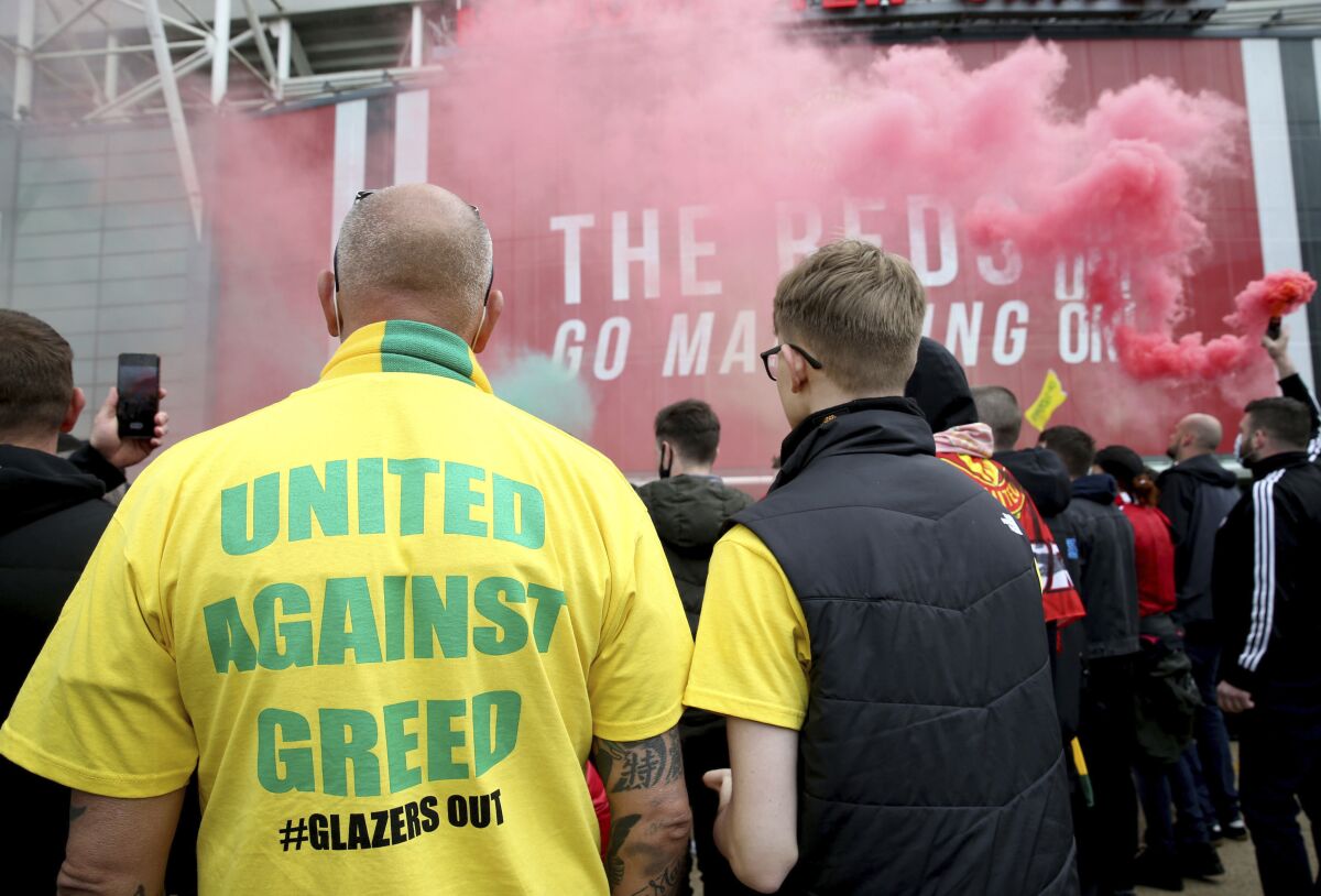 A fan wears a shirt with a "United Against Greed" message, as fans gather to protest against the Glazer family, the owners of Manchester United, outside Old Trafford stadium, in Manchester, England, before their English Premier League match against Liverpool, Sunday, May 2, 2021. Manchester United supporters have stormed into the stadium and onto the pitch ahead of Sunday's game against Liverpool as fans gathered outside Old Trafford to protest against the Glazer ownership. (Barrington Coombs/PA via AP)