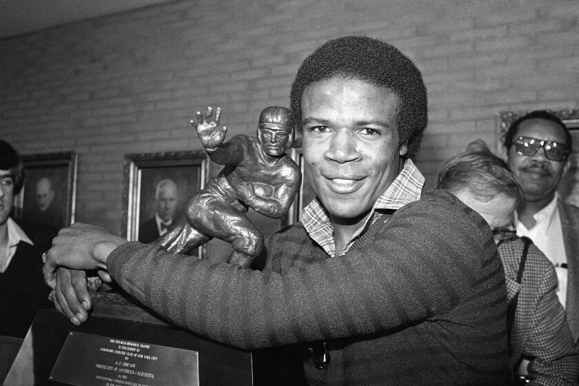 Tailback Charles White of the USC Trojans, puts his arms around the Heisman Trophy won by O.J. Simpson in 1968 after he was announce the winner of the 1979 Heisman Trophy in Los Angeles, Calif., Dec. 3, 1979. White is the second leading rusher in college football history. White's Heisman is the third for USC, along with Simpson and Mike Garrett in 1964. (AP Photo/Wally Fong)