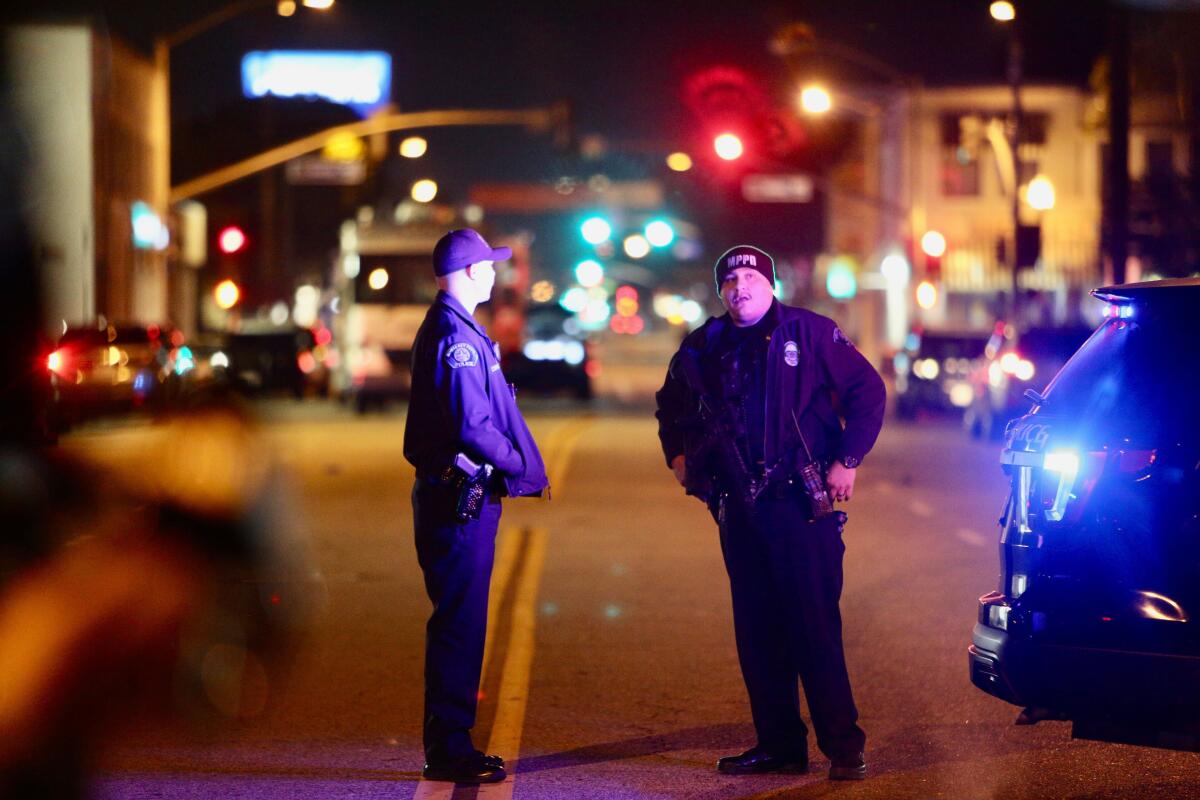 Two police officers stand in the middle of a city street at night.