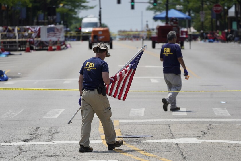 Personal del FBI retira una bandera estadounidense un día después de un tiroteo masivo en Highland Park, Illinois, el martes 5 de julio de 2022. (Foto AP/Charles Rex Arbogast)