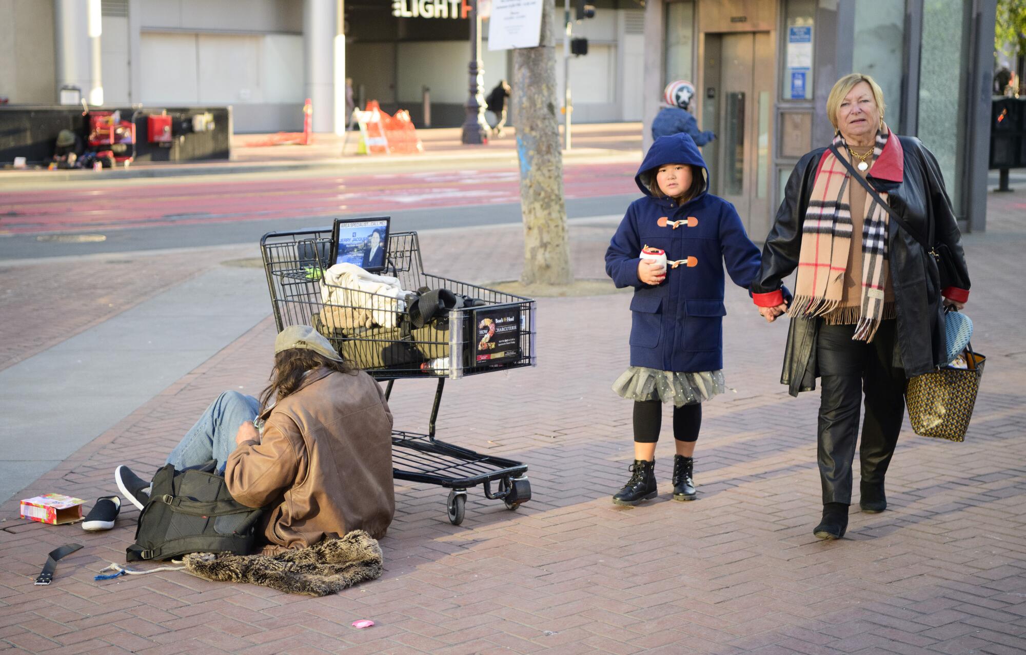 A woman and child walk passed a homeless drug user at UN Plaza in San Francisco.