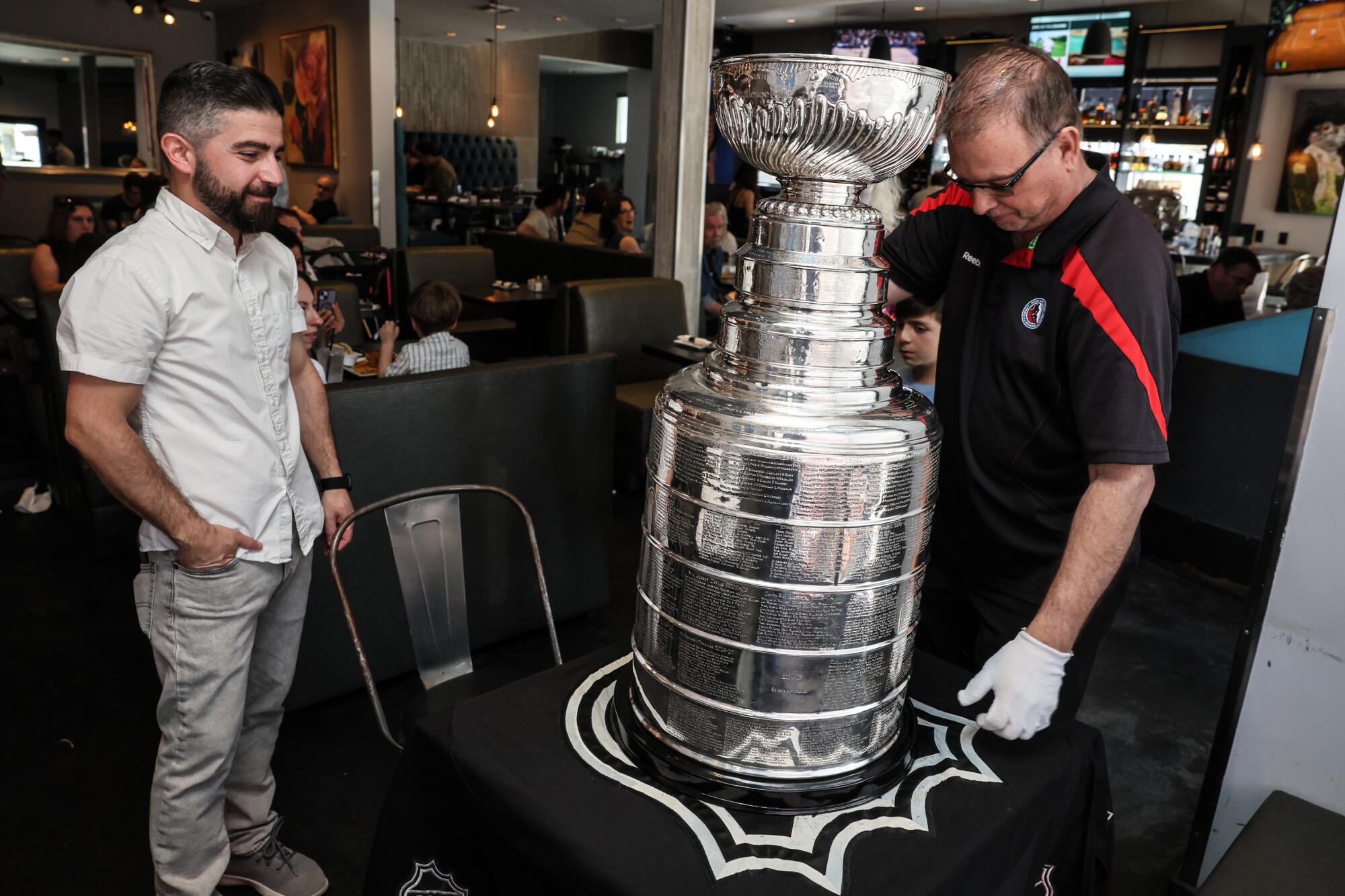 Nareg Dekermenjian, professor at Sherman Oaks, looks at the goalkeeper Stanley Howie Borrow sets up the trophy.