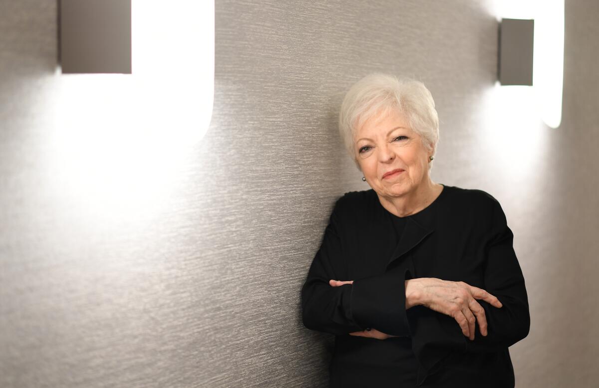 Thelma Schoonmaker, with short-cropped white hair, leans against a blank wall for a portrait.