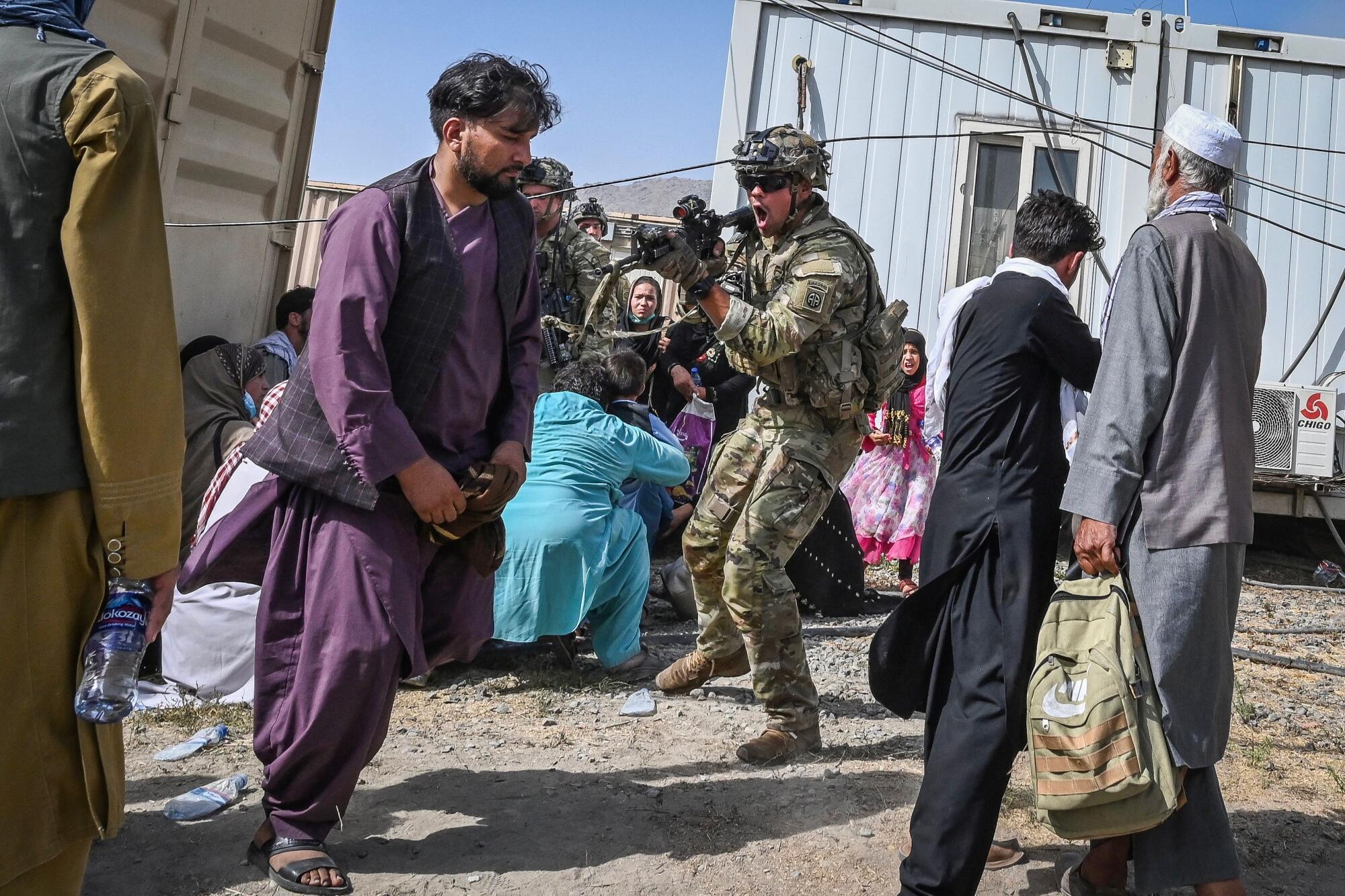 A U.S. soldier points his gun at an Afghan at the Kabul airport.