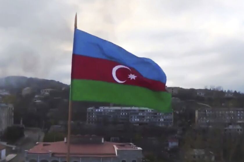 This photo taken from a video released by Azerbaijan's Defense Ministry on Monday, Nov. 9, 2020, shows Azerbaijan's national flag with the city of Shushi in the background, in the separatist region of Nagorno-Karabakh. President Ilham Aliyev said Sunday that Azerbaijani forces had taken control of the strategically important city in Nagorno-Karabakh, where fighting with Armenia has raged for over a month. (Azerbaijan's Defense Ministry via AP)