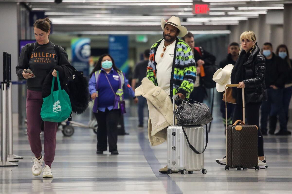 Travelers carry suitcases at an airport.