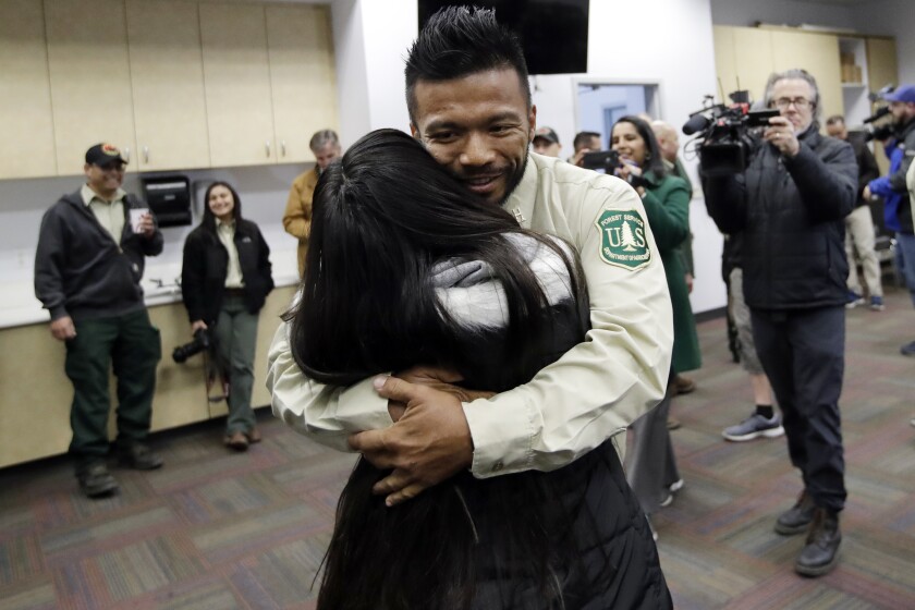 Firefighter Leonard Dimaculangan, of Pasadena, Calif. hugs his daughter Promise, 11, after arriving from a deployment fighting wildfires in Australia Wednesday, Feb. 5, 2020, in Los Angeles. 20 firefighters from the Angeles National Forest worked with the Victoria Rural Fire Service to fight the blazes that are consuming Australia. (AP Photo/Marcio Jose Sanchez)