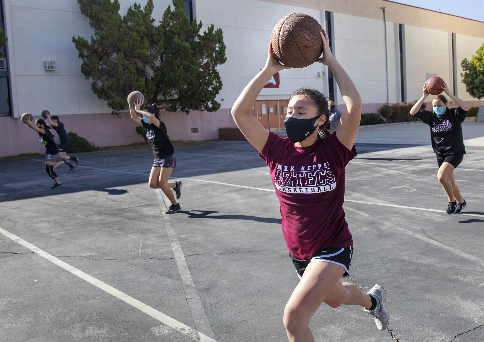 Kendall Tam, foreground, takes part in basketball drills with teammates on an outdoor court 