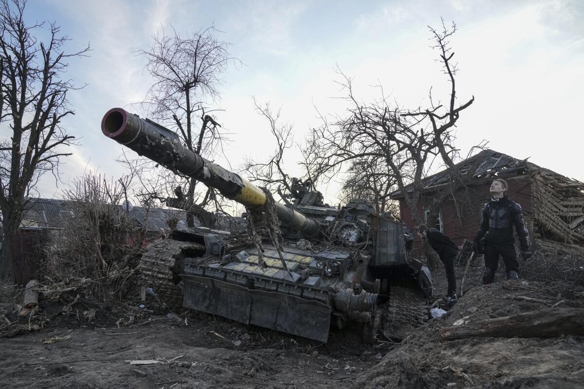 Men stand next to a destroyed tank in Chernihiv, Ukraine.
