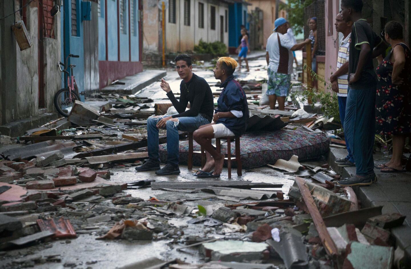 People sit amid debris left by Hurricane Matthew in Baracoa, Cuba. The hurricane rolled across the sparsely populated tip of Cuba overnight, destroying dozens of homes in Cuba's easternmost city and leaving hundreds of others damaged.