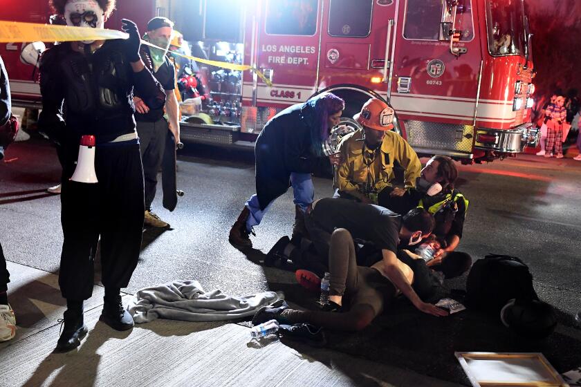 A protester who was hit by a car is attended to as paramedics arrive on Sunset Boulevard.