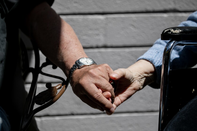 A couple hold hands at a Cinco de Mayo celebration at St. Paul's Senior Services Nursing and Rehabilitation center.