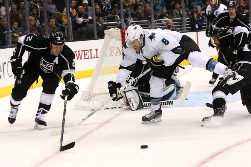 Kings defenseman Matt Greene, left, battles San Jose center Joe Pavelski for a loose puck during the Kings' 4-3 overtime win Wednesday.