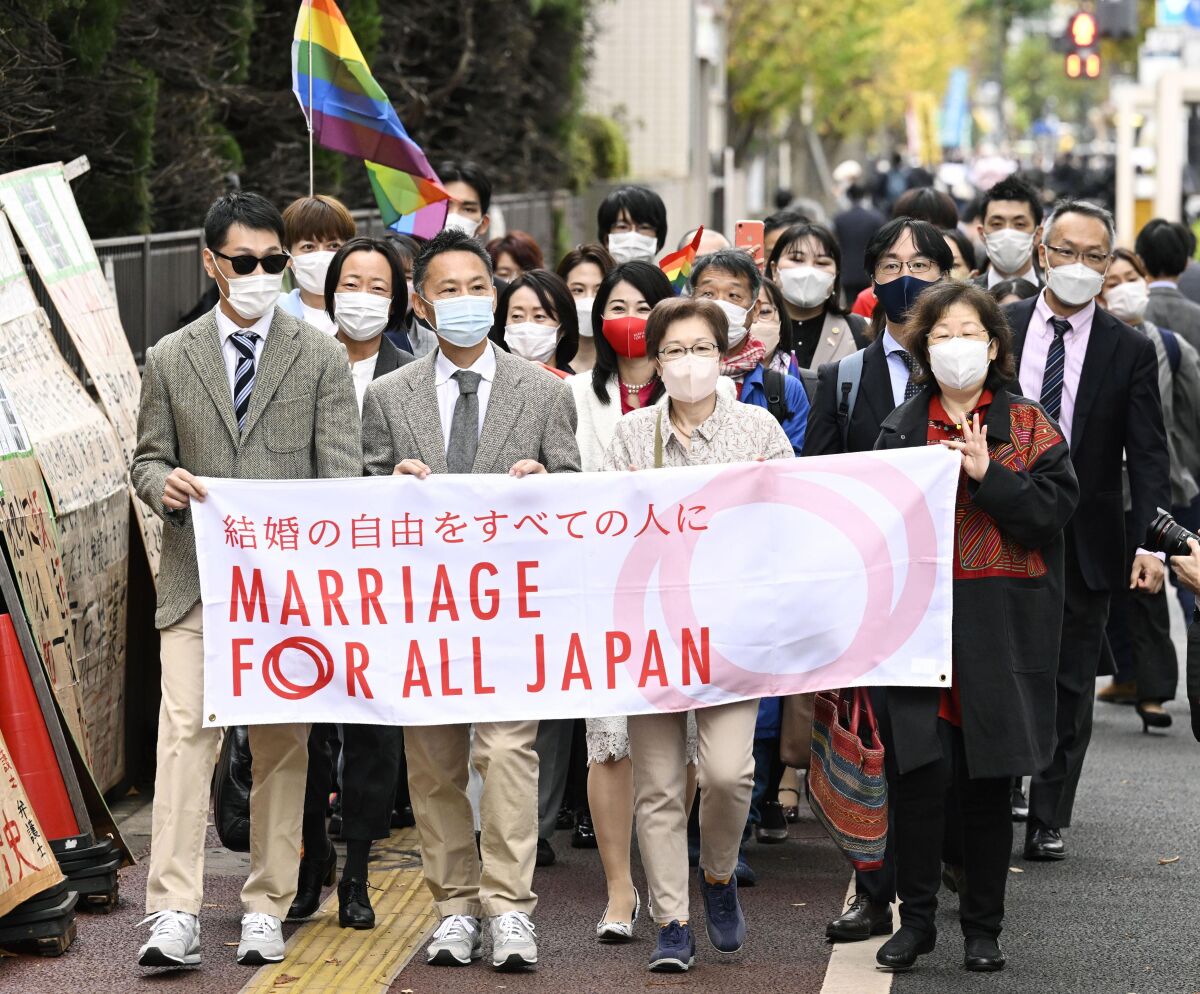 Plaintiffs and supporters walk to the Tokyo district court in Tokyo, Japan, Wednesday, Nov. 30, 2022. Japan's lack of law to protect the right of same-sex couples to marry and become families is unconstitutional, the Tokyo District Court ruled Wednesday in a closely-watched case in a country still largely bound by traditional gender roles and family values.(Kyodo News via AP)