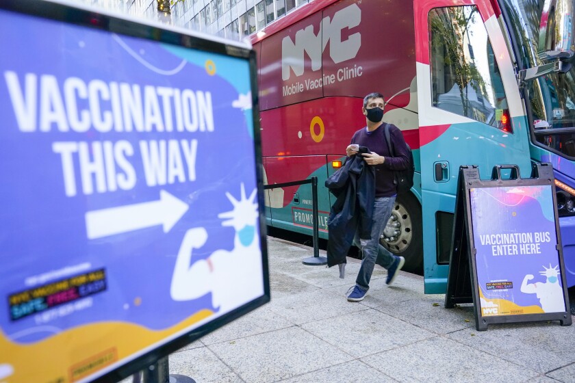A man walks off a vaccination bus at a NYC mobile vaccine clinic in Midtown Manhattan, Monday, Dec. 6, 2021. Mayor Bill de Blasio says all New York City employers will have to mandate COVID-19 vaccinations for their workers by Dec. 27. (AP Photo/Mary Altaffer)