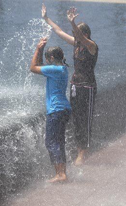 Mekenzie, left, and Melissa Marsh splash back at the fountain.