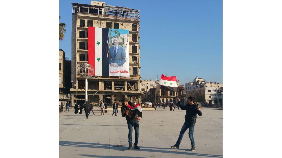 Boys pretend to joust in front of a Syrian government flag in Aleppo.